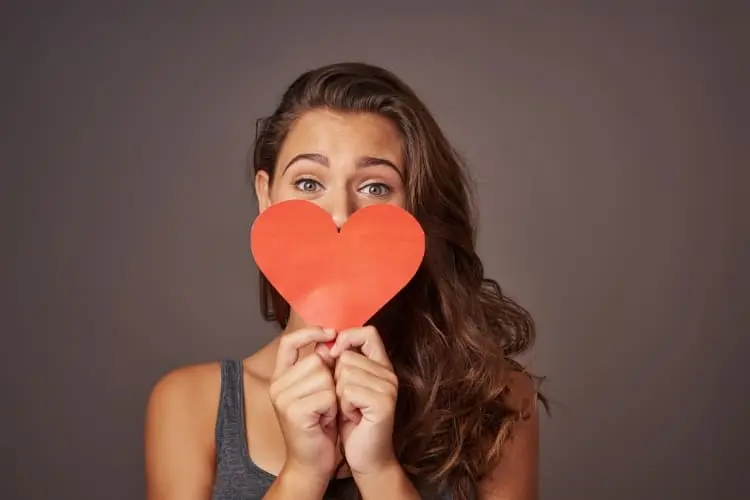 young lady with red paper heart in front her face in NeverFail Dating